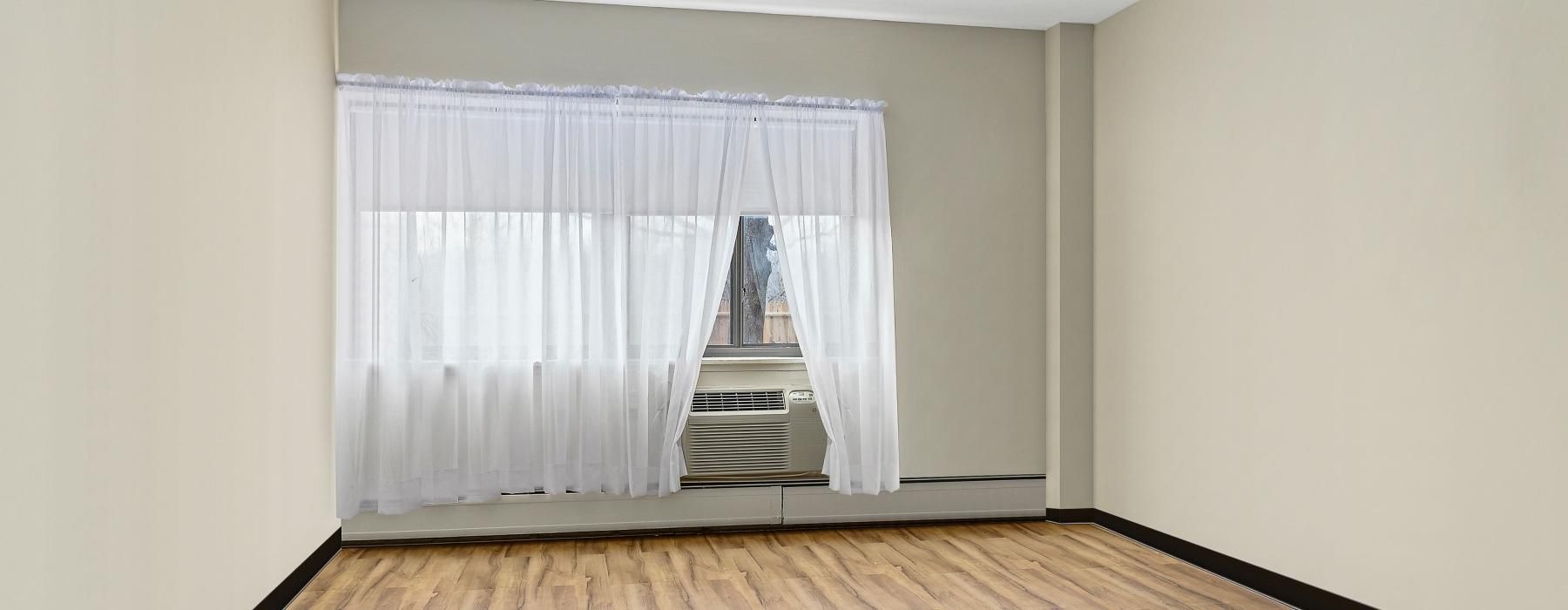 a room with a wood floor and a wood floor with a white curtain
